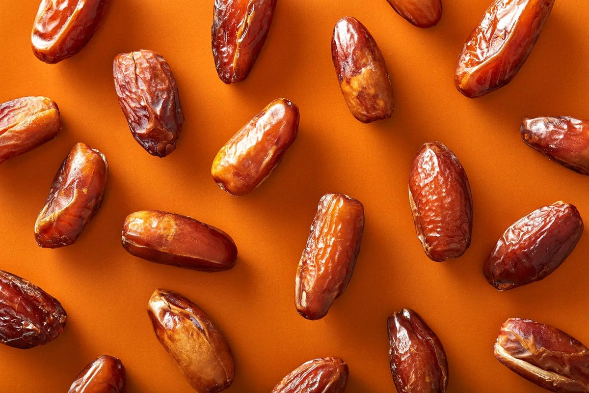 Tunisian Deglet Noor dates scattered on an orange background